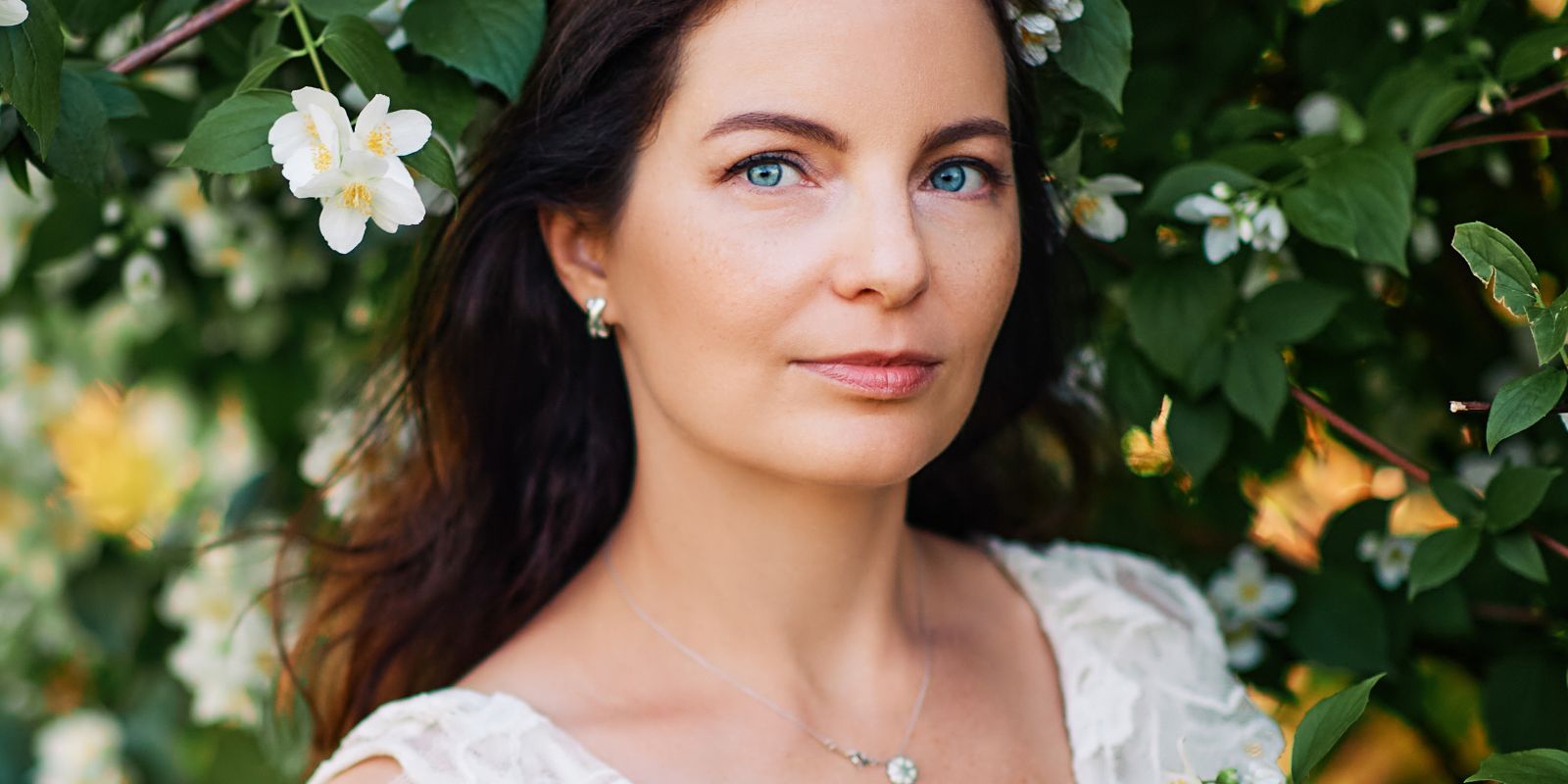 Beautiful woman with blue eyes standing by a tree