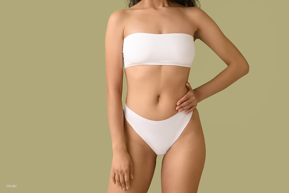 Curvy woman in white underwear against a green background